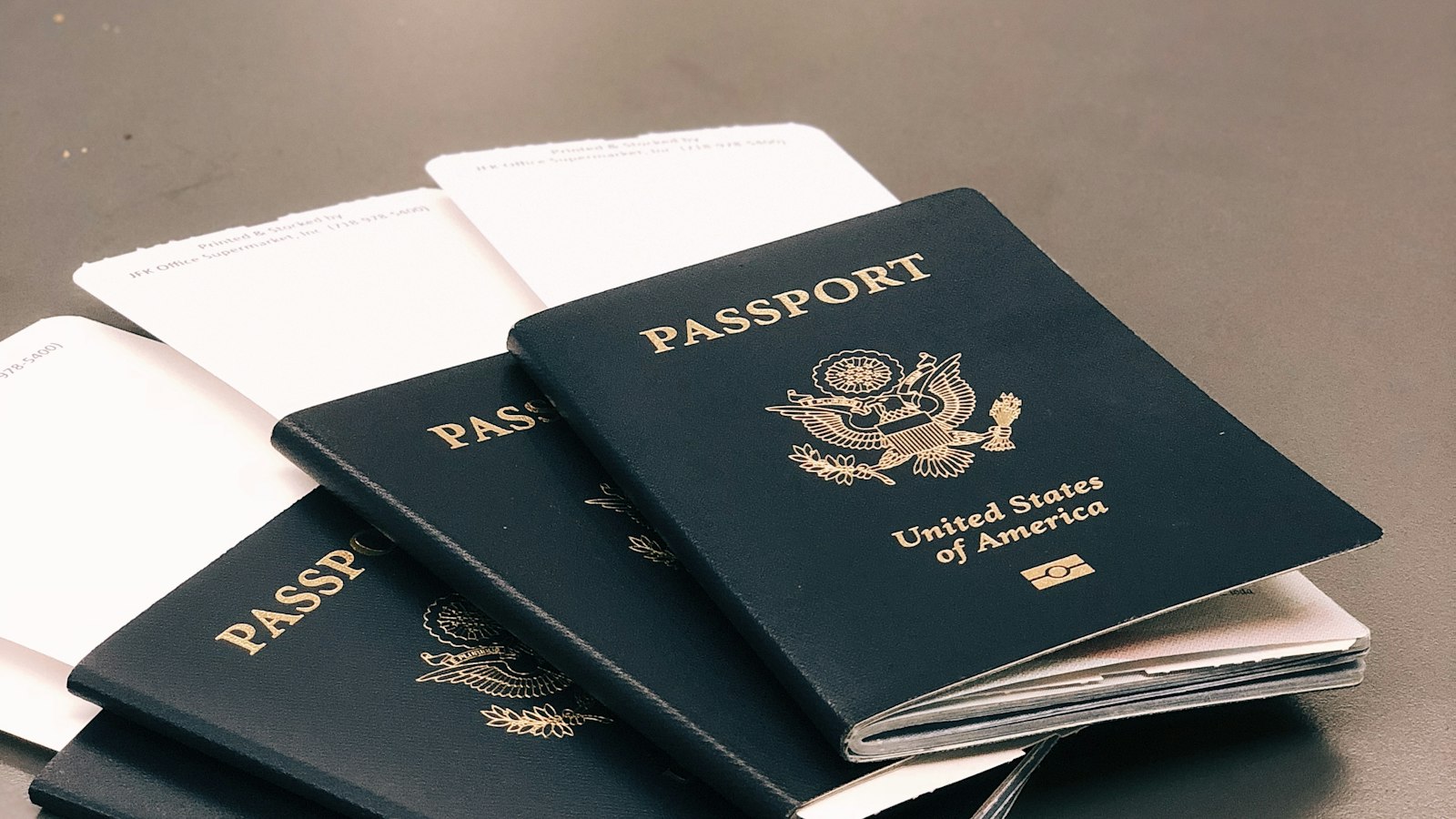 Four passports and blank forms fanned out on a dark surface