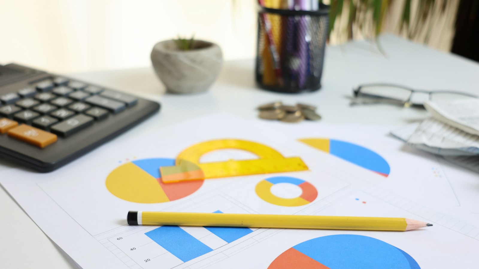 A desk with a calculator, printed charts and a pencil